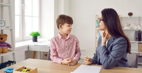 Child learning correct pronunciation with speech therapist.